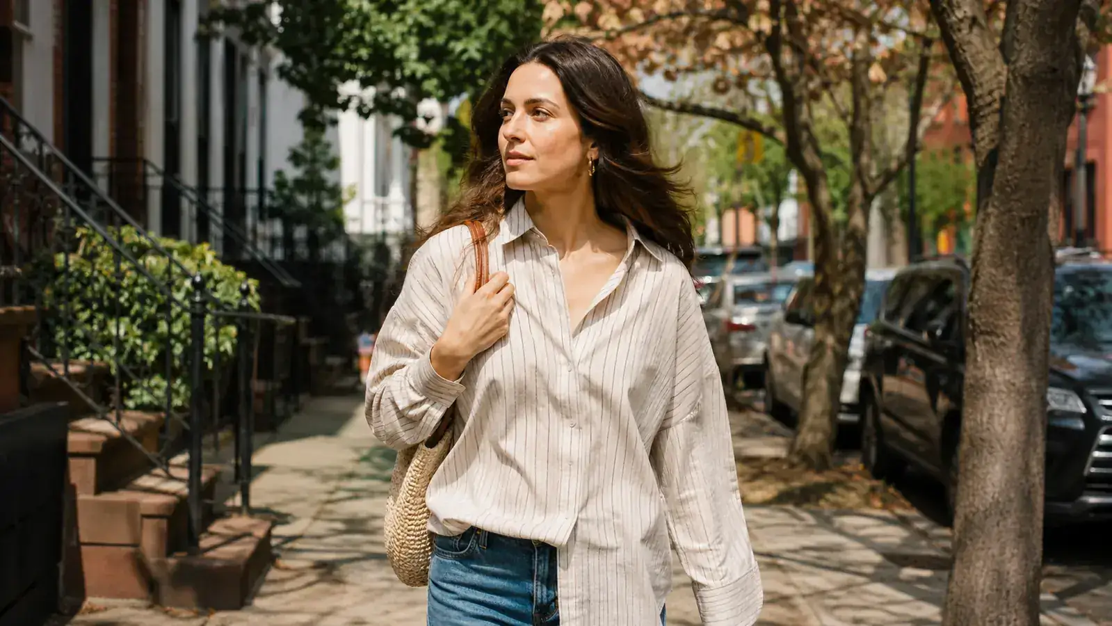 Woman on a Brooklyn sidewalk in morning light wearing light makeup, glowing skin, no visible white cast